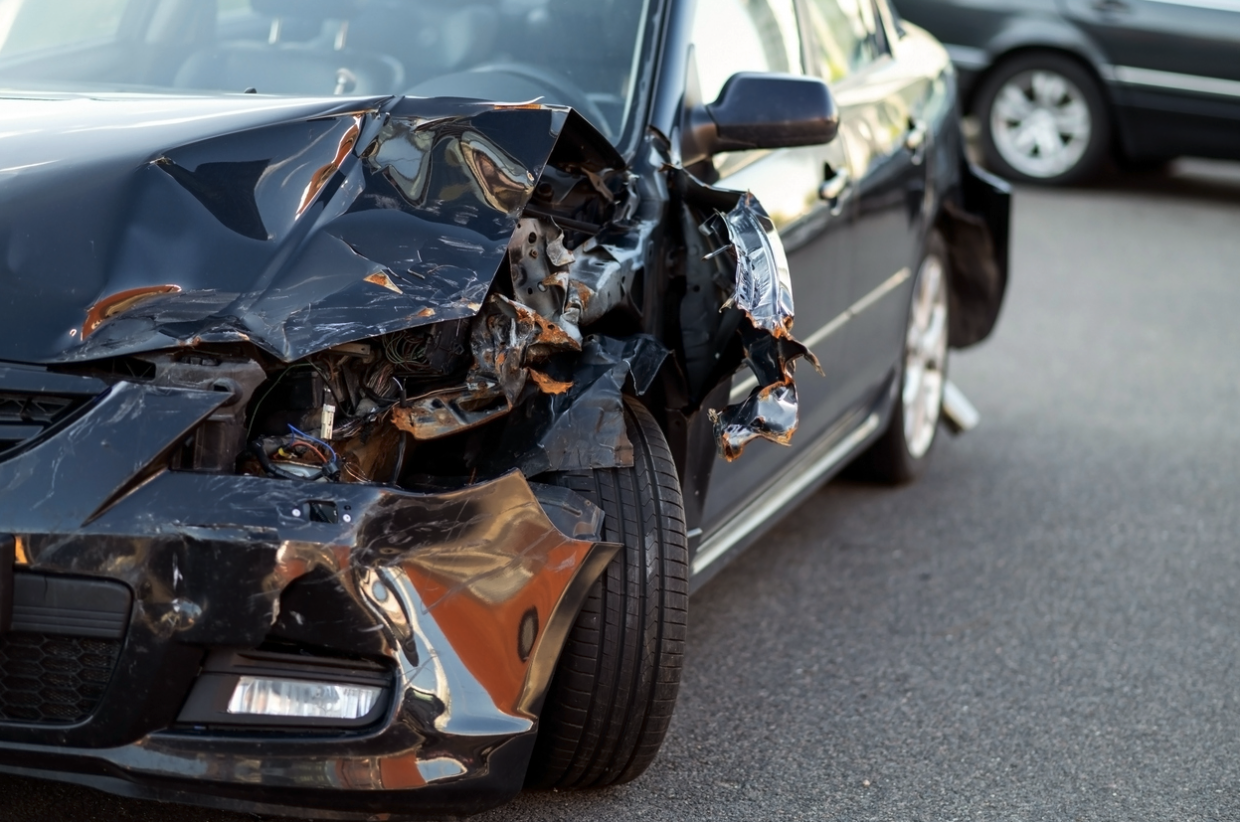 A damaged front end of a black car after a car accident